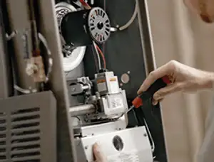 Furnace repair technician inspecting internal components and wiring in Greensboro, NC