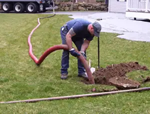 Septic pumping technician servicing a residential septic tank with a vacuum hose in Greensboro, NC