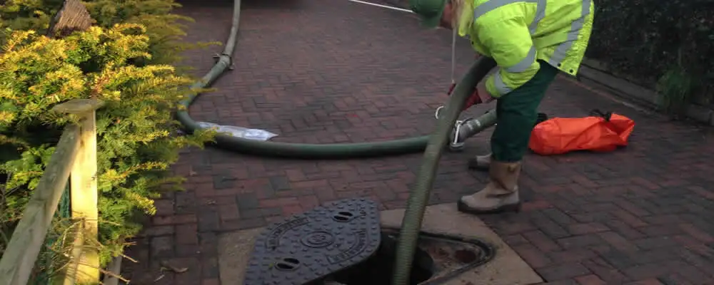 Septic tank cleaning technician servicing a septic tank with a vacuum hose in Greensboro, NC
