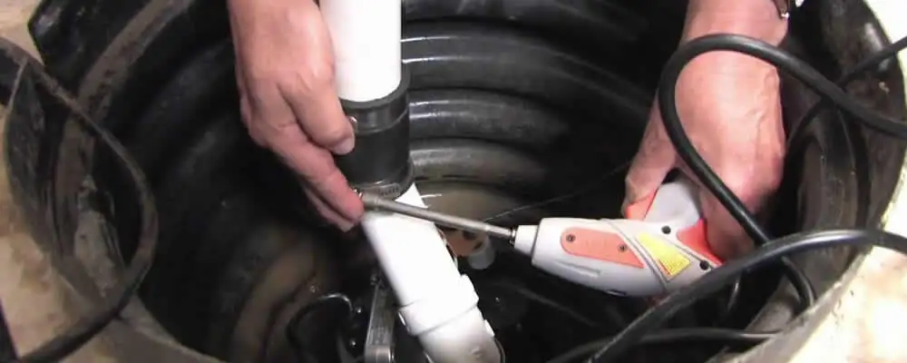 Sump pump installation technician connecting PVC discharge piping in Greensboro, NC