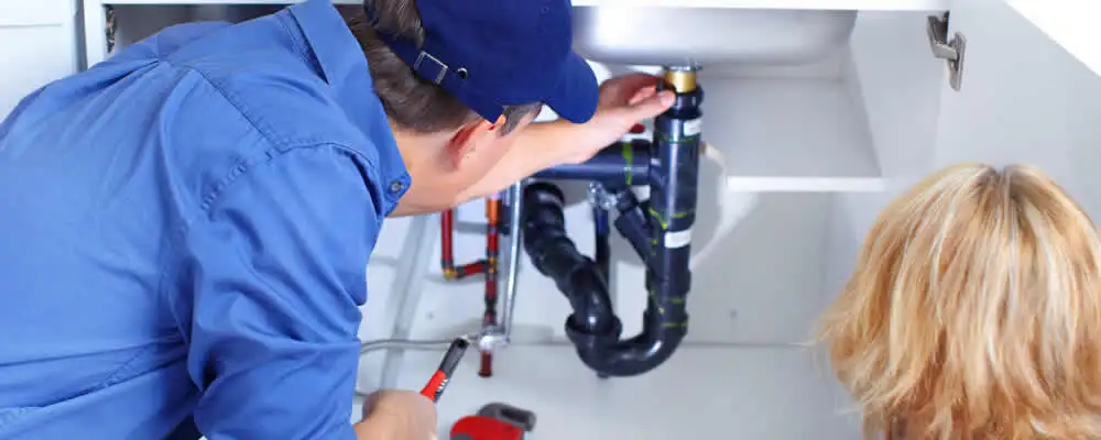 Plumber repairing under-sink drain pipes and fittings in Greensboro, NC